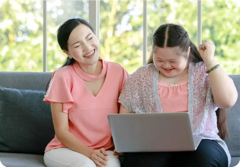 Caregiver looking at a laptop with a girl.