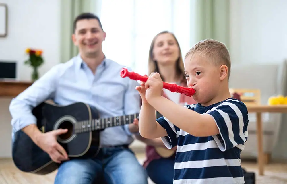 Boy with down syndrome playing instruments with his family.