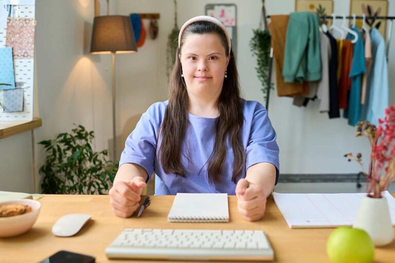 Happy young female with down syndrome sitting at a desk.