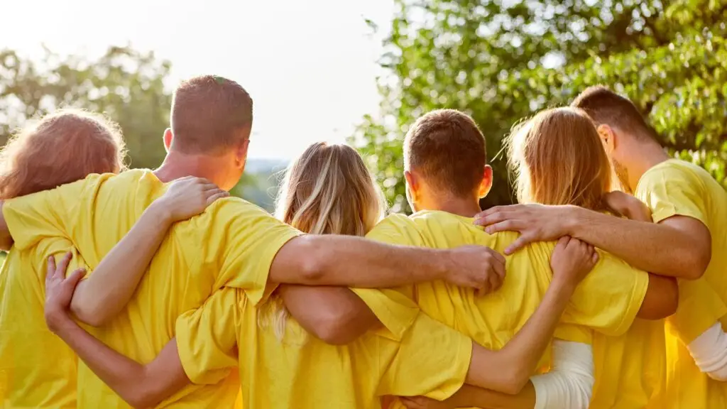 image of a group of people from behind so you can see arms around each other like a team